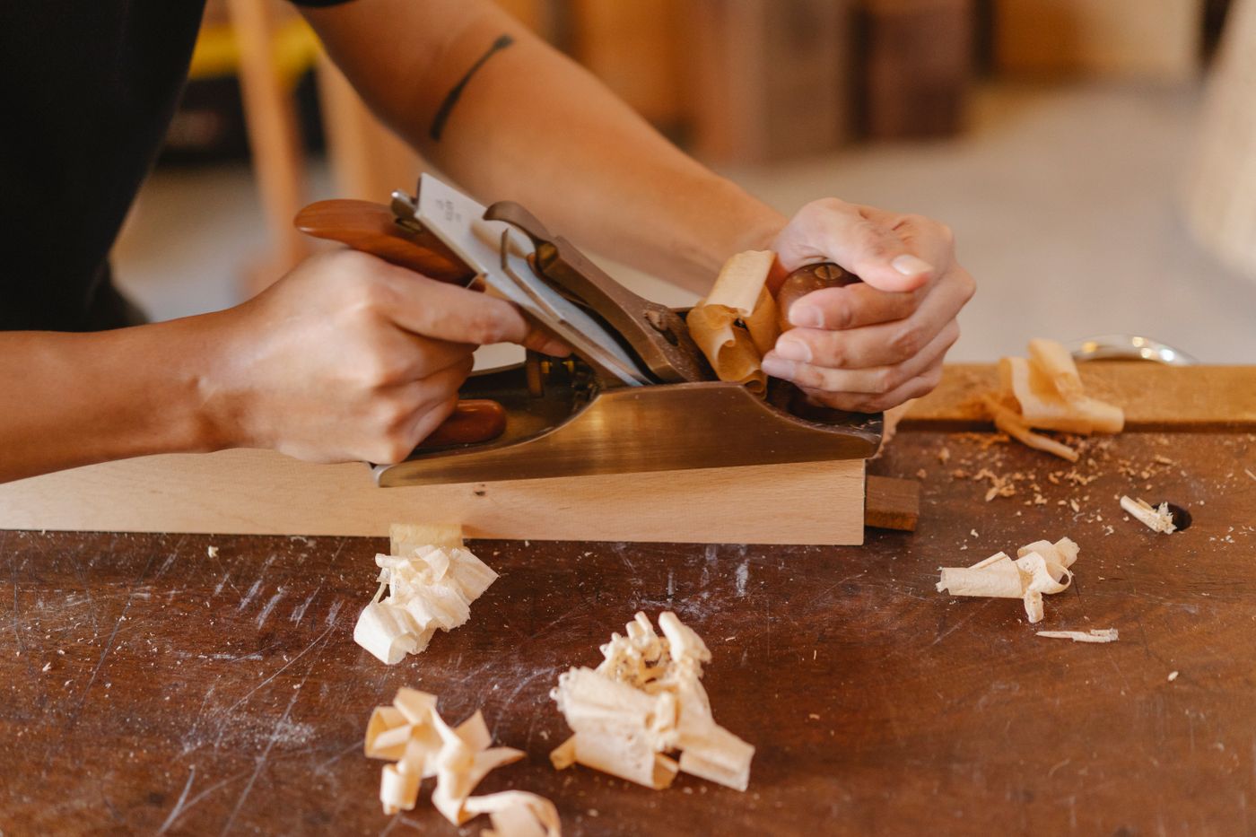 Hand-planing a board, shavings curling off the blade